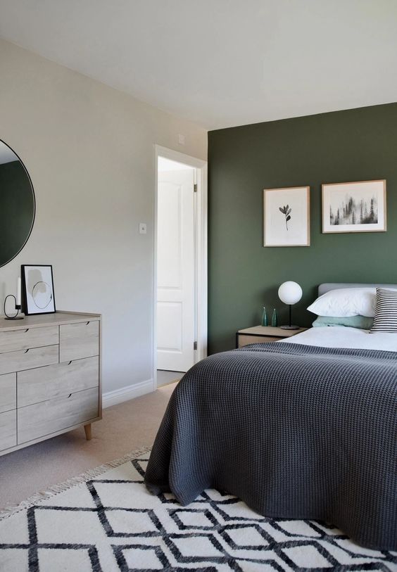 a bedroom with a green accent wall, a grey bed with bold bedding, a whitewashed dresser and a mini gallery wall for an eye-catchy touch