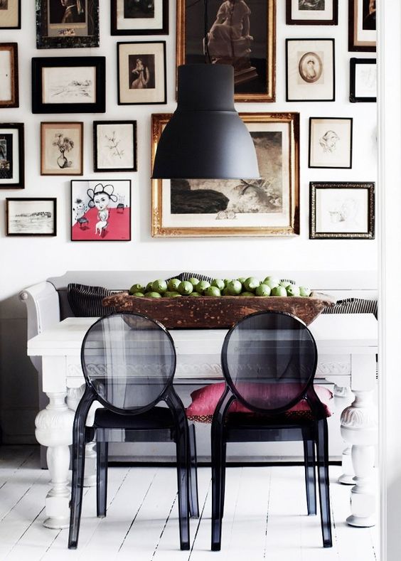 a bold Scandinavian dining room with a white vintage table, black sheer chairs, a black pendant lamp and a gorgeous oversized gallery wall