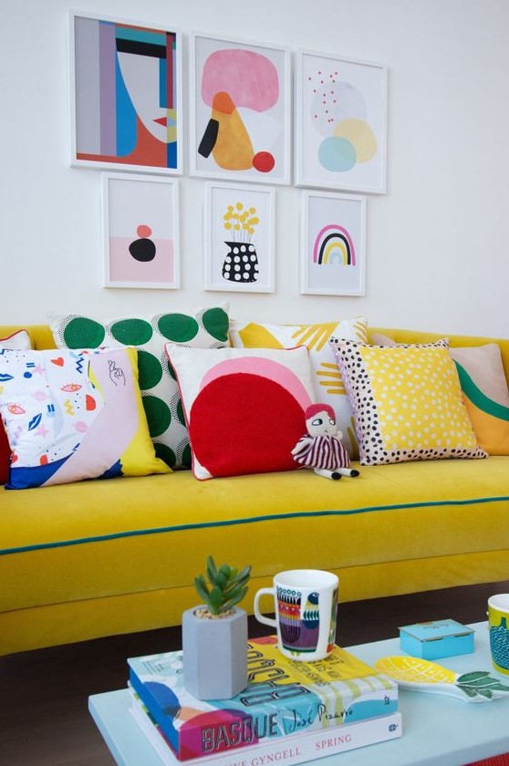 a bold gallery wall with abstract prints in various colors adds interest to the bright couch zone