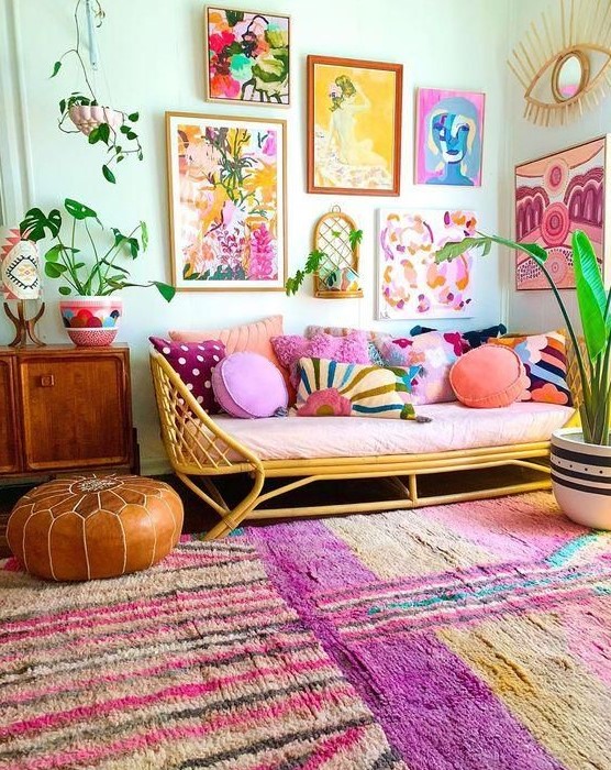 a bright and colorful gallery wall with mismatching frames, bold floral and naive artworks and greenery is a cool idea for a boho space
