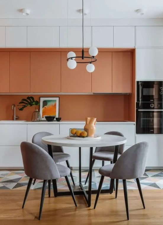 a bright contemporary kitchen with orange and white sleek cabinets, an orange backsplash and white countertops, a geo tile floor