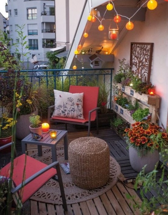 a bright eclectic terrace with a couple of metal chairs and side tables, a rug, lights and potted blooms and greenery