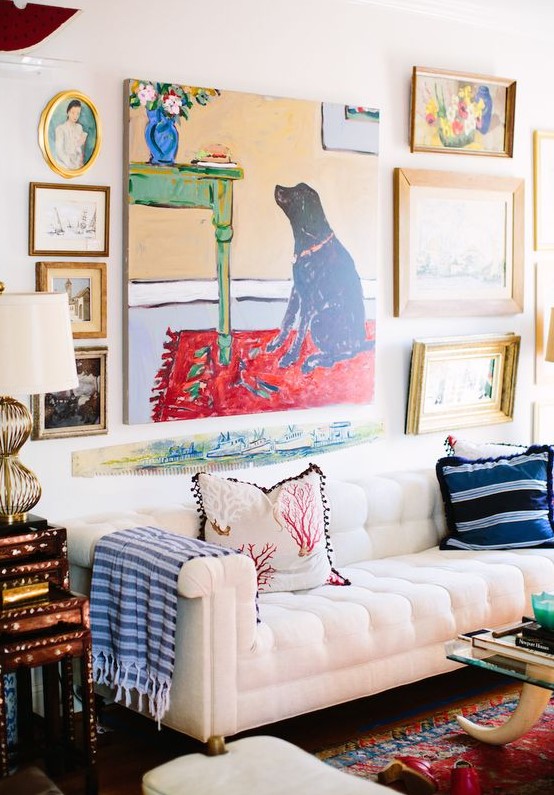a bright gallery wall with a bold non-framed artwork in the center and some mismatching artworks around