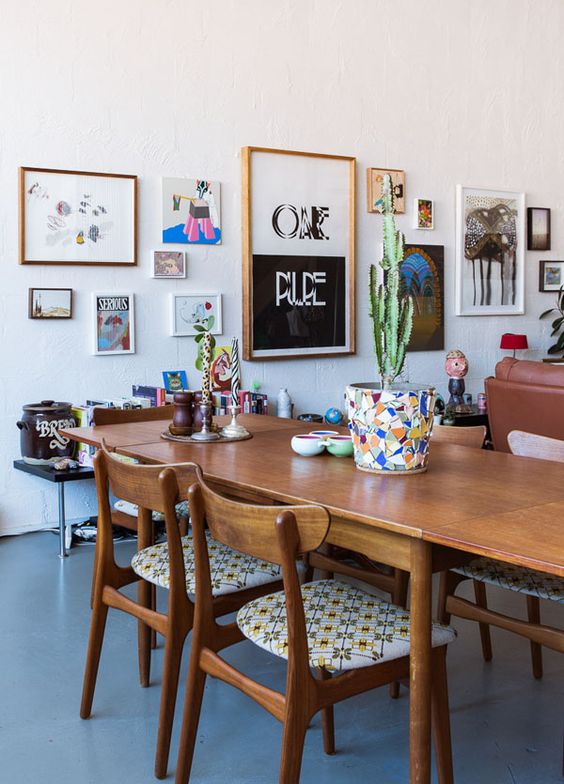 a catchy modern dining room with stained furniture, a colorful gree form gallery wall and potted plants