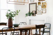 a charming vintage dining room with a vintage table and mismatching chairs, a faux fireplace and a mini gallery wall over it