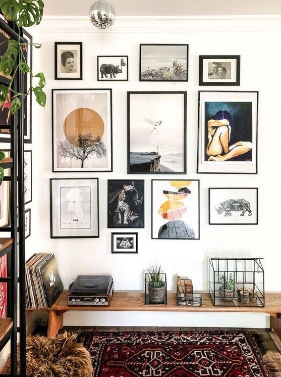 a chic free form gallery wall with thin black frames, white matting and various types of art presented