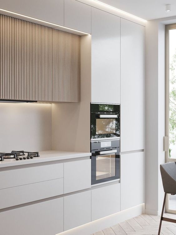 a chic minimalist kitchen with no hardware cabinets, wood slat ones, built in appliances and lights is a perfect space to be in