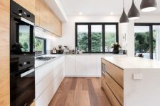 a chic minimalist kitchen with no hardware white cabinets, a sleek kitchen island with a stone countertop, a window backspalash and black lamps