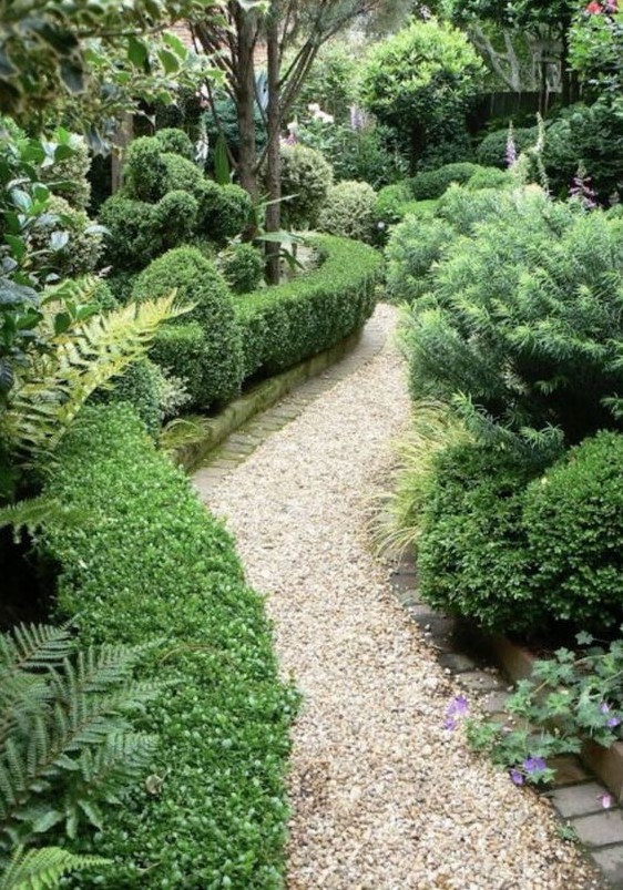 a chic neutral-colored gravel pathway with brick lining in a lush garden is a cool idea that allows drainage