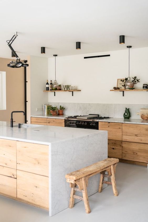 a chic neutral contemporary kitchen with light-stained no hardware cabinets, a waterfall kitchen island and black fixtures