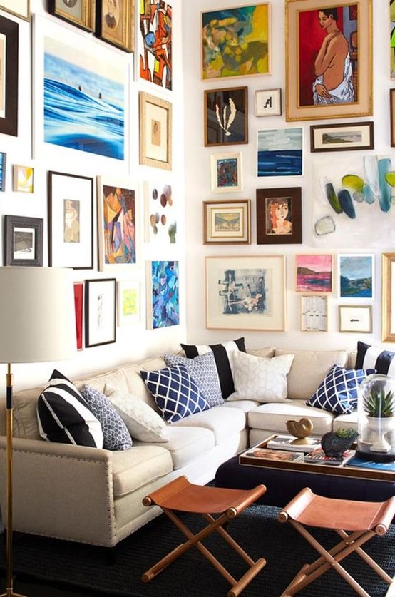 a colorful gallery wall taking two walls with mismatching frames and super bold artworks in various styles and in various colors