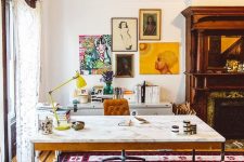 a colorful home office with a marble desk, a leather chair and a wooden stool, a built-in fireplace, a credenza, a colorful gallery wall