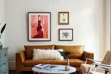 a colorful living room with a rust-colored leather sofa, beige chairs, a round table, a pink rug and a blue inlay dresser, a whimsical mini gallery wall
