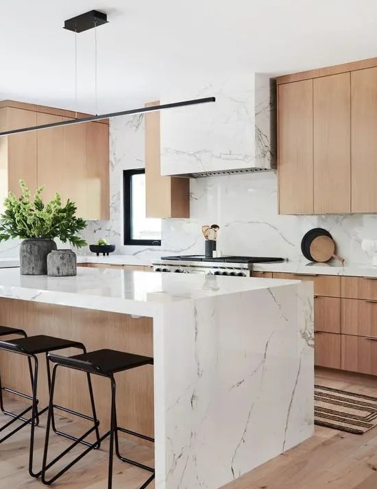 a contemporary kitchen with elegant light-stained cabinets, a white stone hood and countertops plus a bakcsplash and a matching kitchen island