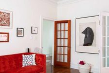 a contrasting living room with a hot red sofa, a vintage coffee table, a mini gallery wall and a statement artwork on another wall