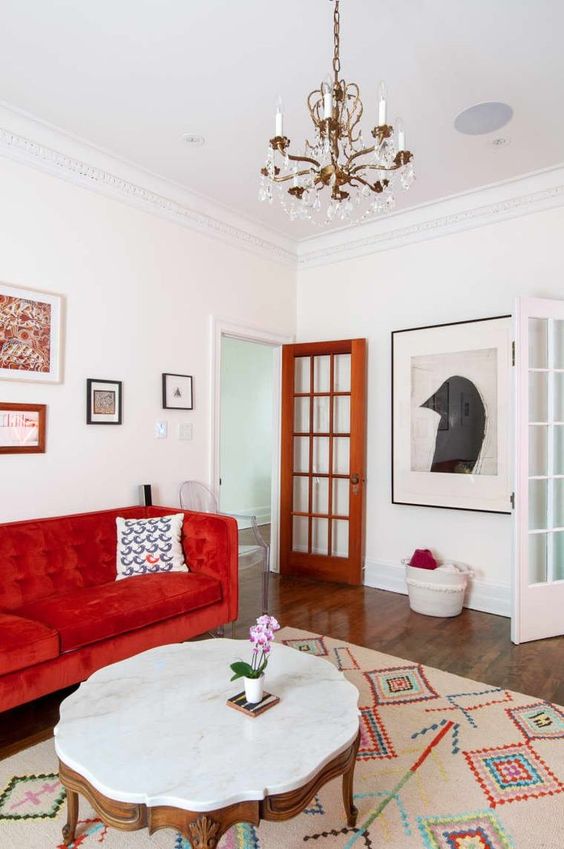 a contrasting living room with a hot red sofa, a vintage coffee table, a mini gallery wall and a statement artwork on another wall