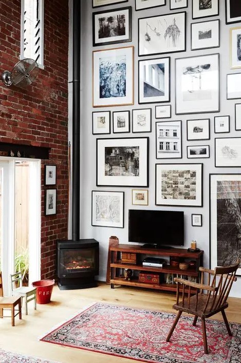 a cool gallery wall done with matching neutral and black frames of various sizes and with prints is a stylish idea