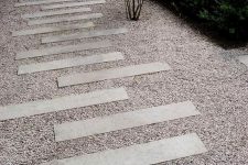 a cool gravel pathway with concrete steps and greenery and shrubs around is a lovely solution for a modern outdoor space