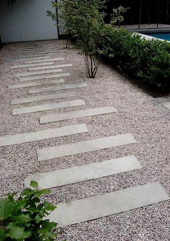 a cool gravel pathway with concrete steps and greenery and shrubs around is a lovely solution for a modern outdoor space