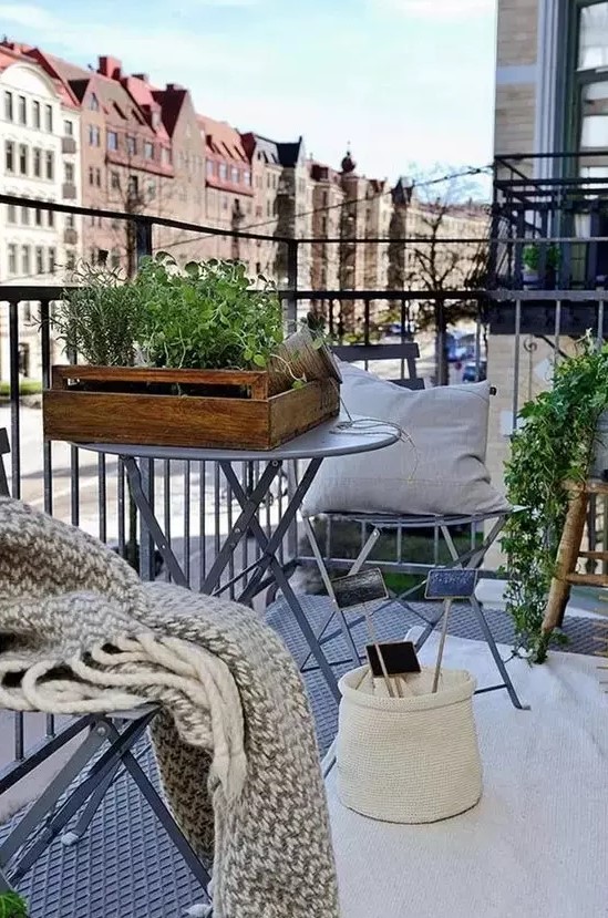 a cozy Scandi balcony, a rug, pillows, throws, potted plants and tiny coffee tables for winter