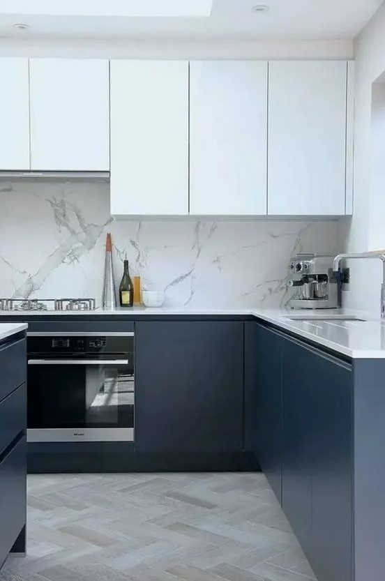 a fab contemporary kitchen with sleek white and navy cabinets, a white stone backsplash and countertops and a skylight