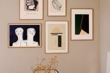 a free form modern gallery wall with thin gilded frames and graphic artworks for a chic modern touch in the space