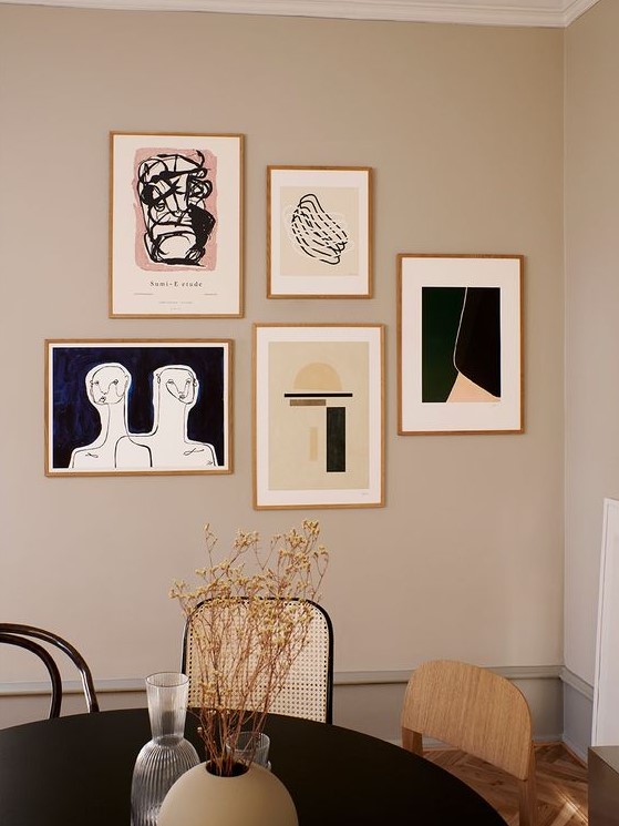 a free form modern gallery wall with thin gilded frames and graphic artworks for a chic modern touch in the space
