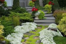 a front yard pathway of stone decorated with moss and with white blooms lining up the path