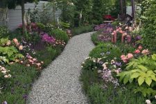 a gravel pathway lined by lush greenery and blooms looks like a path ina magical forest