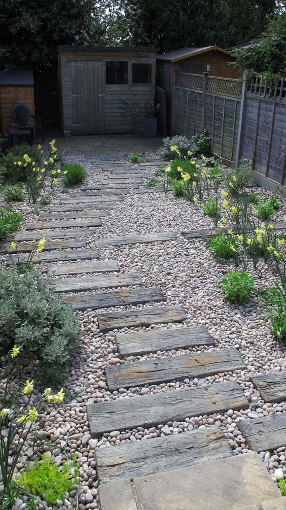 a gravel pathway with some reclaimed wood steps, greeneyr and blooms around is a cool idea for a rustic outdoor space