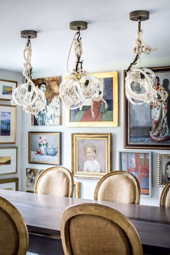 a jaw-dropping dining room with a simple table and vintage chairs, whimsical rope pendant lamps and artworks all over the space
