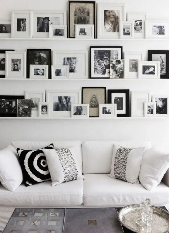 a large Scandinavian gallery wlal with white ledges, black and white artworks in various black and white frames