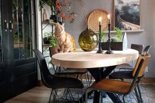 a lovely Scandinavian dining room with a taupe accent wall, a light-stained oval table, mismatching chairs and open shelving