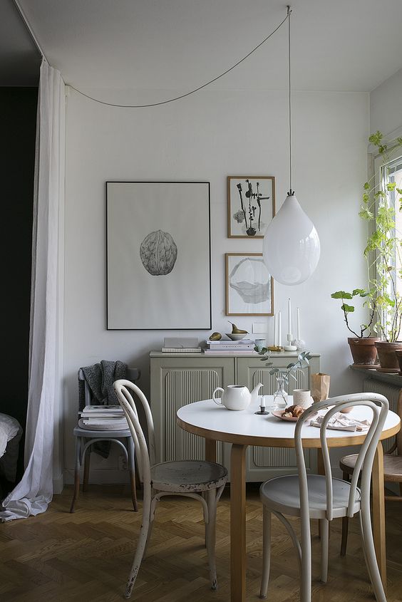 a lovely Scandinavian dining zone with a grey cabinet, a round table and vintage chairs, a mini gallery wall and some greenery