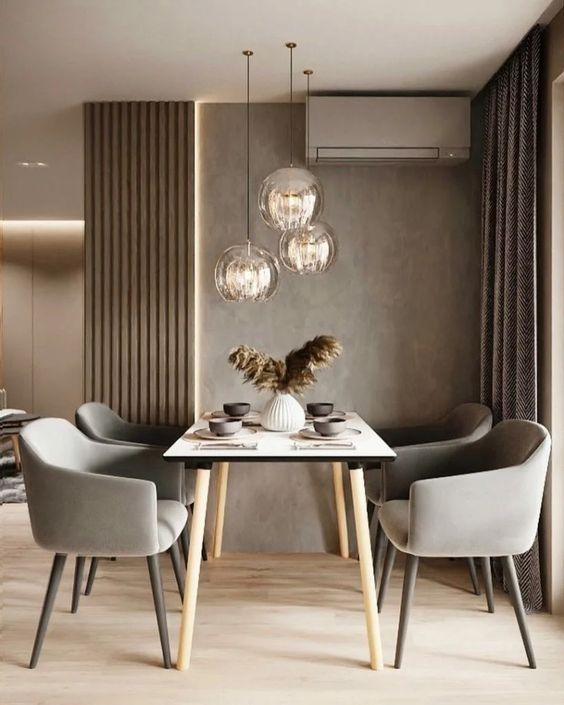 a lovely and welcoming taupe dinign zone with taupe walls, paneling and curtains, a simple table and grey chairs plus pendant lamps