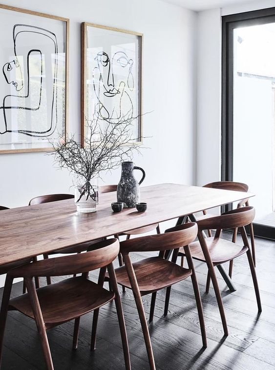 a lovely mid-century modern dining space with a stained table and chairs, a mini graphic gallery wall and a glazed wall