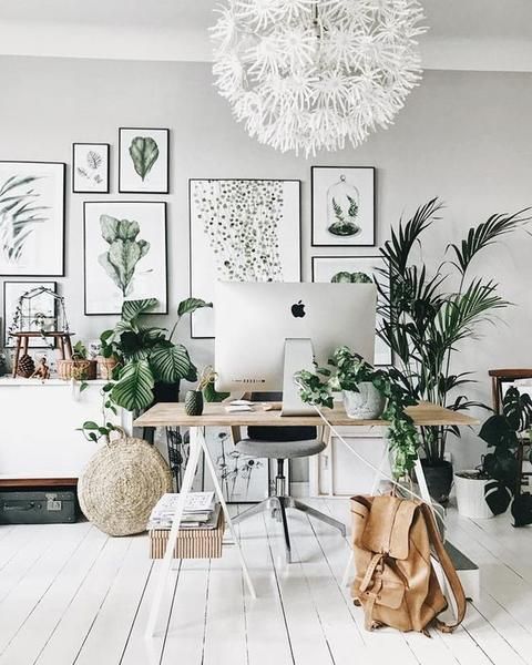 a lovely neutral home office with a lightweight desk, a grey chair, a botanical gallery wall, some potted plants and a floral chandelier