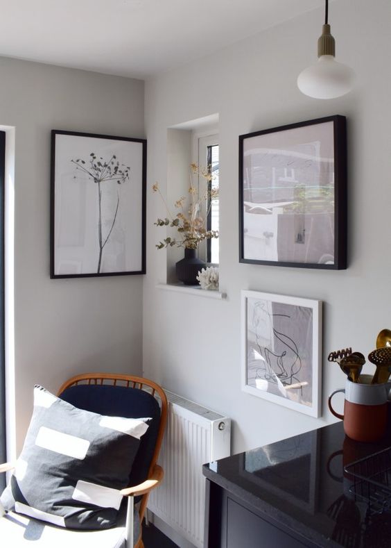 a lovely nook with a black chair with a pillow, a mini gallery wall and some dried blooms and plants