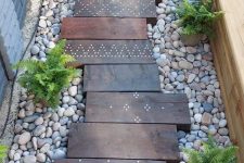 a lovely walkway with dark-stained wooden steps, neutral pebbles, potted greeneyr is a gorgeous idea for a boho outdoor space