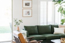 a mid-century modern living room with a grene sofa, a brown leather chair, a mini gallery wall and some greenery