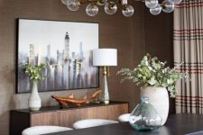 a mid-century modern taupe dining room with a credenza, a dark table and creamy chairs, a lovely chandelier