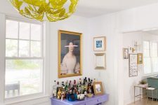 a mini gallery wall over the lilac home bar and a second one in the next room accent each space in a cool way