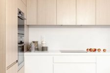 a minimalist kitchen with light-stained and white cabinets, built-in appliances and white countertops is a lovely space to be in