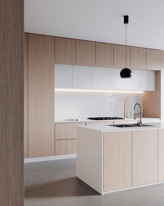 a minimalist neutral kitchen with sleek no hardware cabinets, a matching kitchen island, a hex tile backsplash and black fixtures