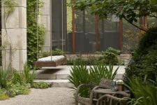 a modern and a bit rustic garden with lots of greenery and trees, with reclaimed wood furniture and a gravel path plus stone steps