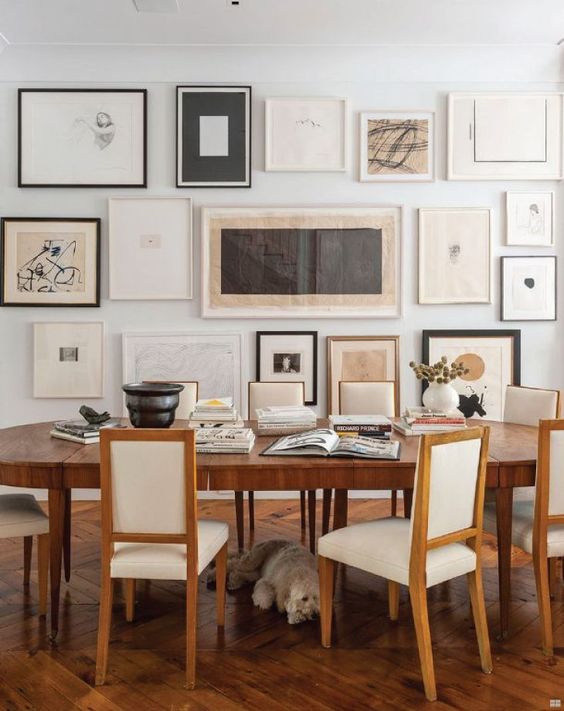 a neutral vintage dining room with a stained table and creamy chairs, a large free form gallery wall and some dried blooms