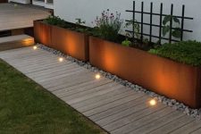 a neutral wooden garden path with a perfectly manicured lawn on one side and metal garden planters placed on pebbles on the other creates a chic modern look