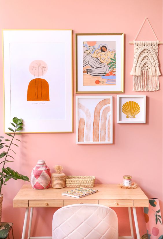 a pink boho home office with a bright gallery wall, a small and cute desk, a blush chair and some boho touches