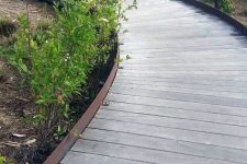 a reclaimed wood curved wooden walkway with a metal side is a lovely idea for a rustic-inspired outdoor space