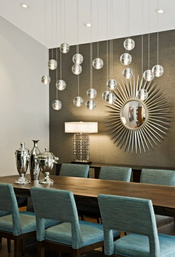 a refined formal dining room with a taupe accent wall, a dark stained table and turquoise chairs, bubble lights and a mirror